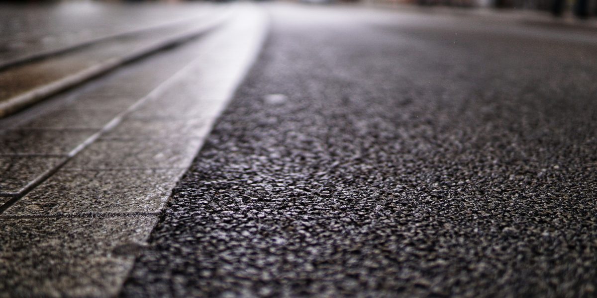 High angle shot of an asphalt road texture and a stone sidewalk Asphalt Pavement Maintenance